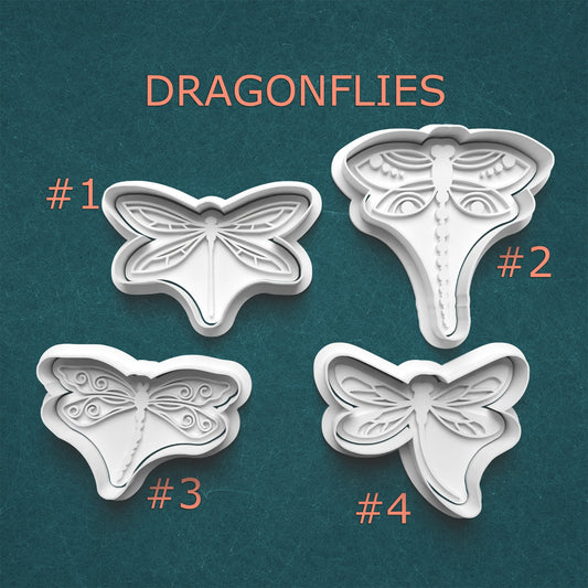 Four dragonfly-shaped cookie cutters on a teal background