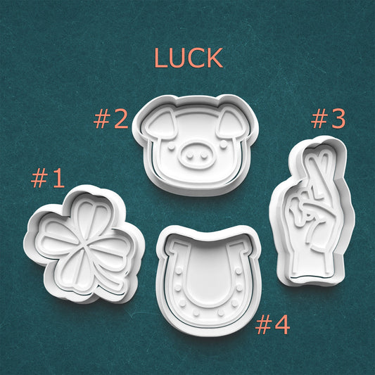 Four lucky-themed cookie cutters on a teal background with 'LUCK' text.