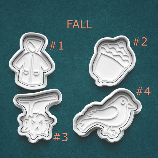 Four cookie cutters with fall-themed designs on a teal background