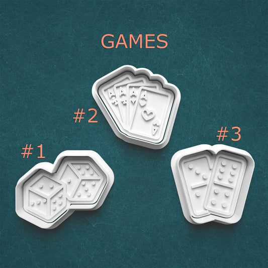 Three white game-themed cookie cutters on a teal background with 'GAMES' text above.