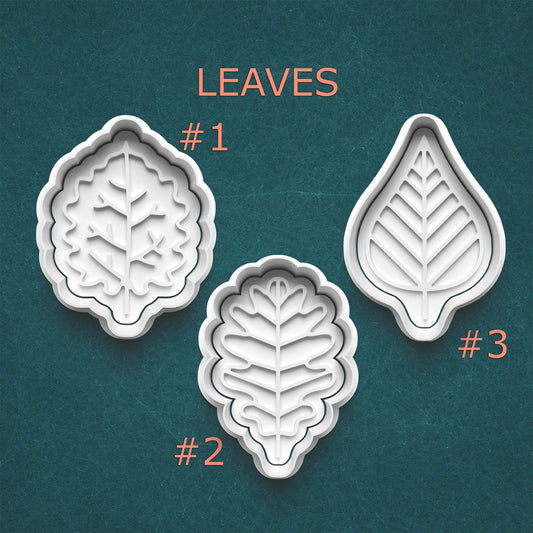 Three leaf-shaped cookie cutters on a teal background