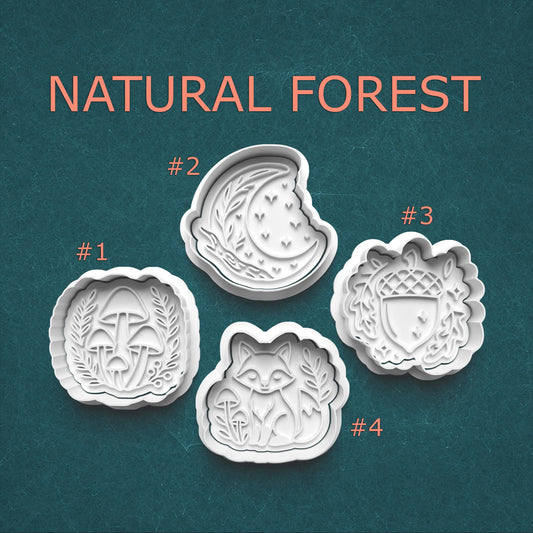 Four cookie cutters with natural forest designs on a teal background