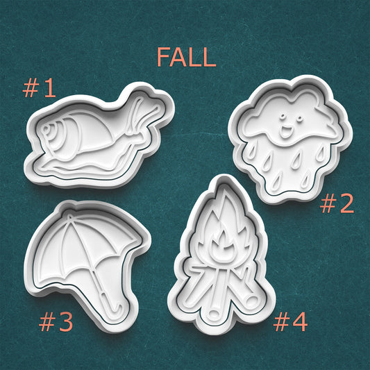 Four cookie cutters with fall-themed designs on a teal background