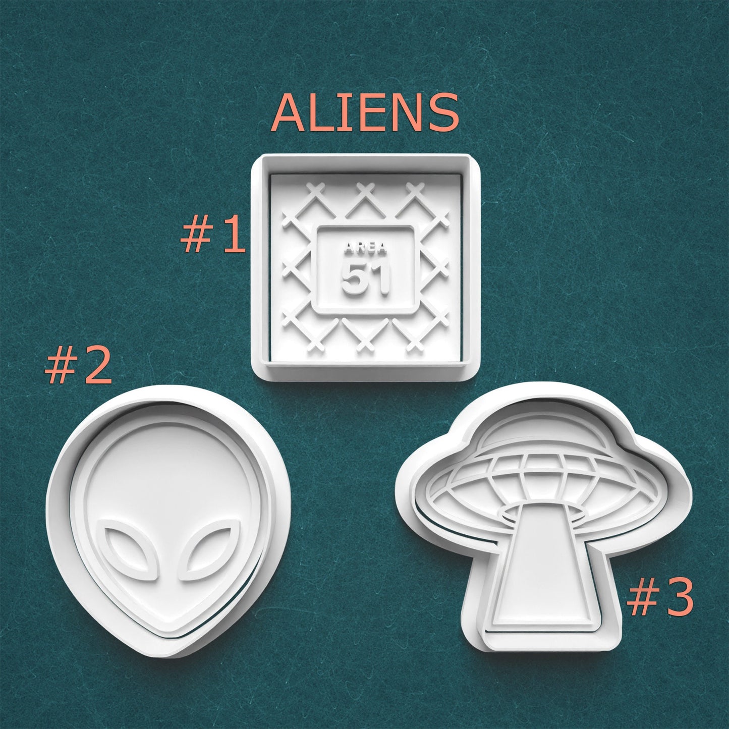 Three cookie cutters shaped like aliens on a teal background