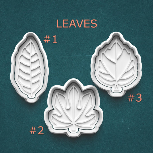 Three leaf-shaped cookie cutters on a teal background