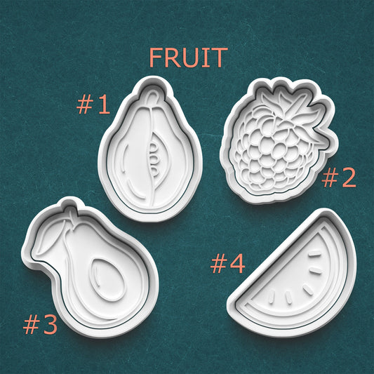 Four fruit-shaped cookie cutters on a teal background