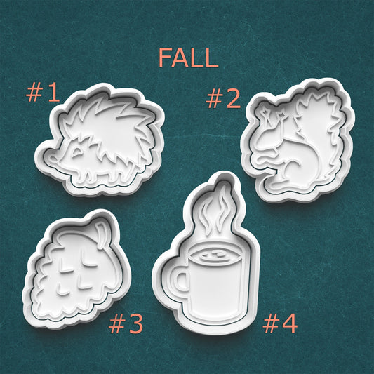 Four cookie cutters with fall-themed designs on a teal background