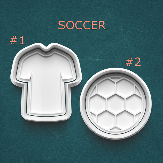 Two cookie cutters shaped like a soccer jersey and a soccer ball on a teal background.