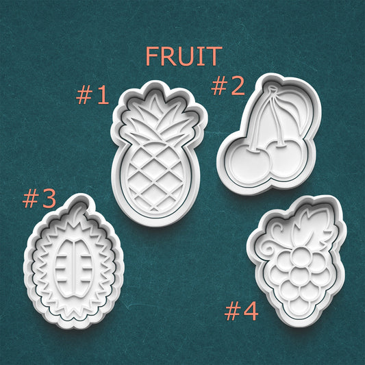 Set of four fruit-shaped cookie cutters on a teal background