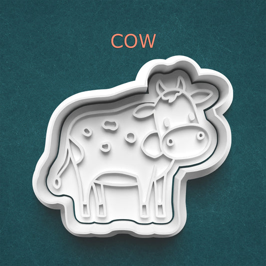 Cow-shaped cookie cutter on a teal background with 'COW' text above