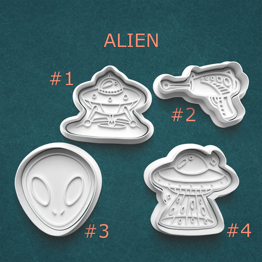 Four alien-themed cookie cutters on a teal background