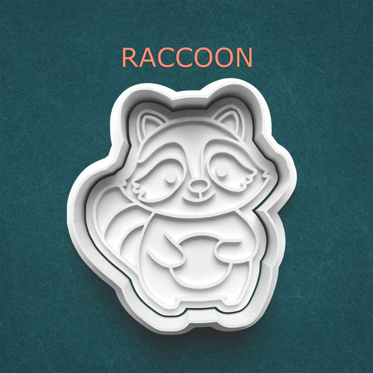 Raccoon-shaped cookie cutter on a teal background with 'RACCOON' text above.