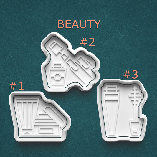 Three beauty product-shaped cookie cutters on a teal background with 'BEAUTY' text.
