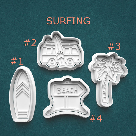 Set of four cookie cutters shaped like a beach sign, palm tree, surfboard, and camper on a teal background with 'Surfing' text.