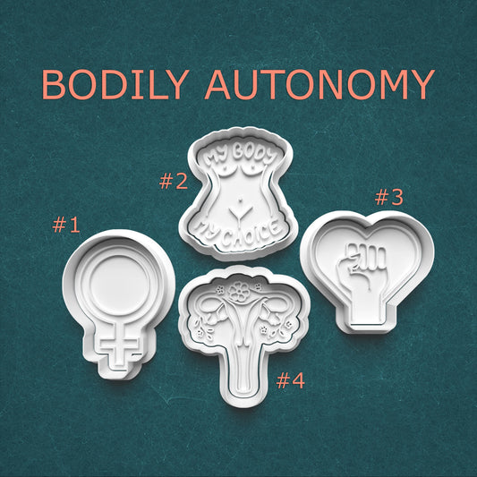 Four cookie cutters with symbolic designs and text on a teal background, labeled 'BODILY AUTONOMY'.