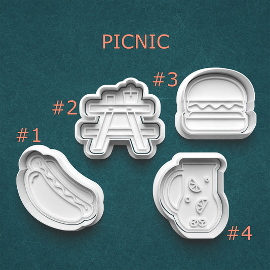 Set of four cookie cutters shaped like picnic items on a teal background with 'PICNIC' text.
