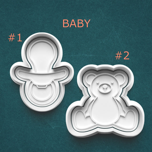 Two cookie cutters shaped like a baby and a teddy bear on a teal background.
